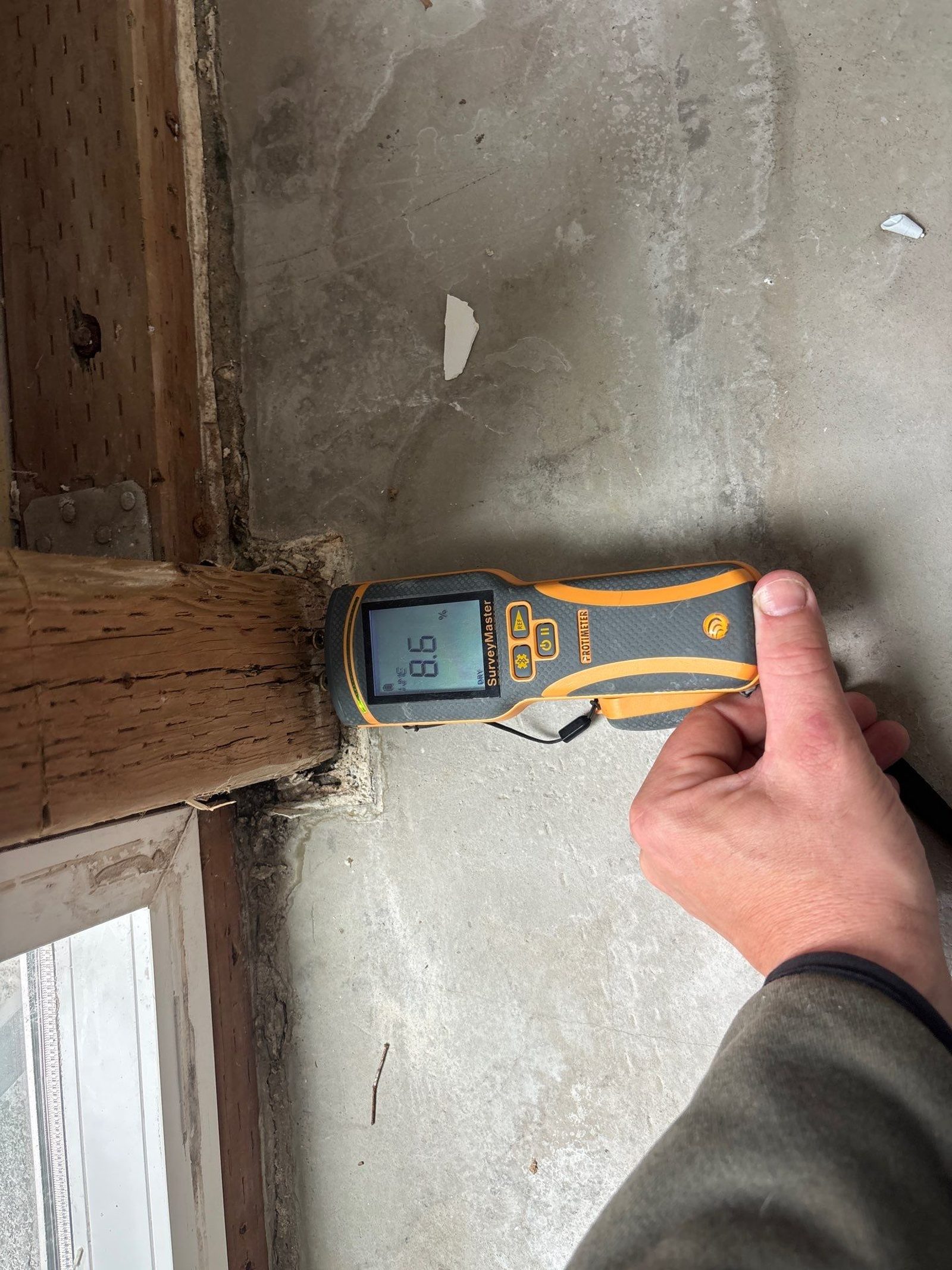 Inspector taking a moisture meter reading on a water damaged wall
